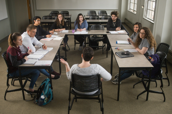 小教室里的学生聚集在一个有桌子的长方形教室里